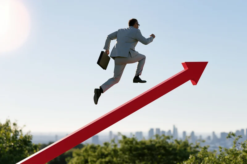 Businessman in light grey suit running with briefcase along red upward arrow against city skyline