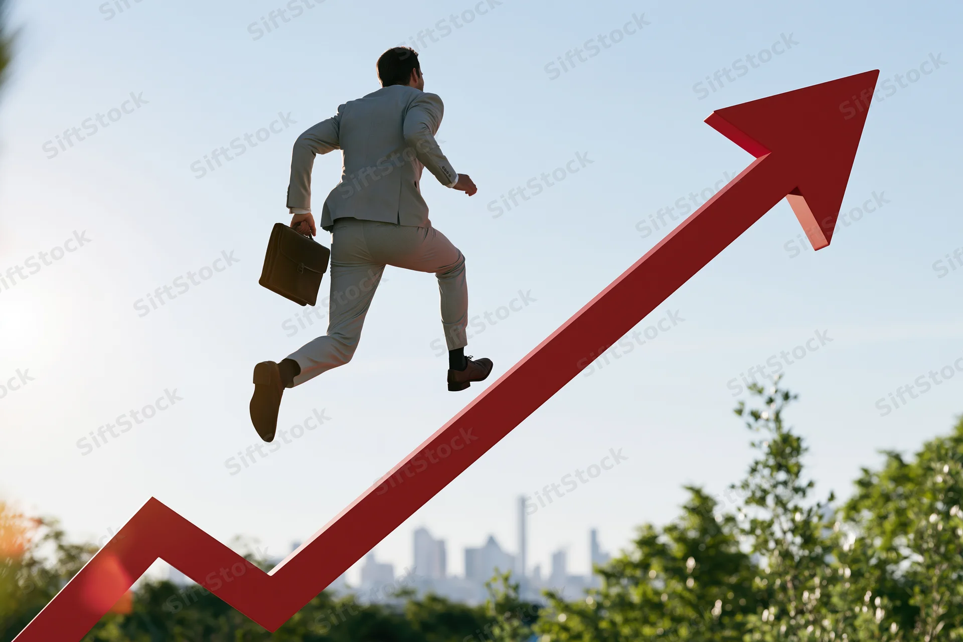Businessman in light grey suit running with briefcase up red upward arrow against city skyline