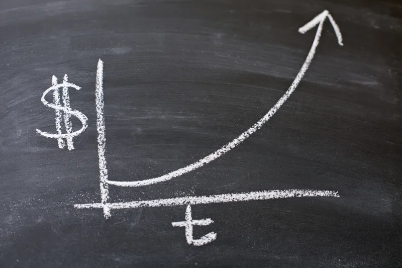 Chalk-drawn exponential growth graph on a blackboard with dollar and time axes