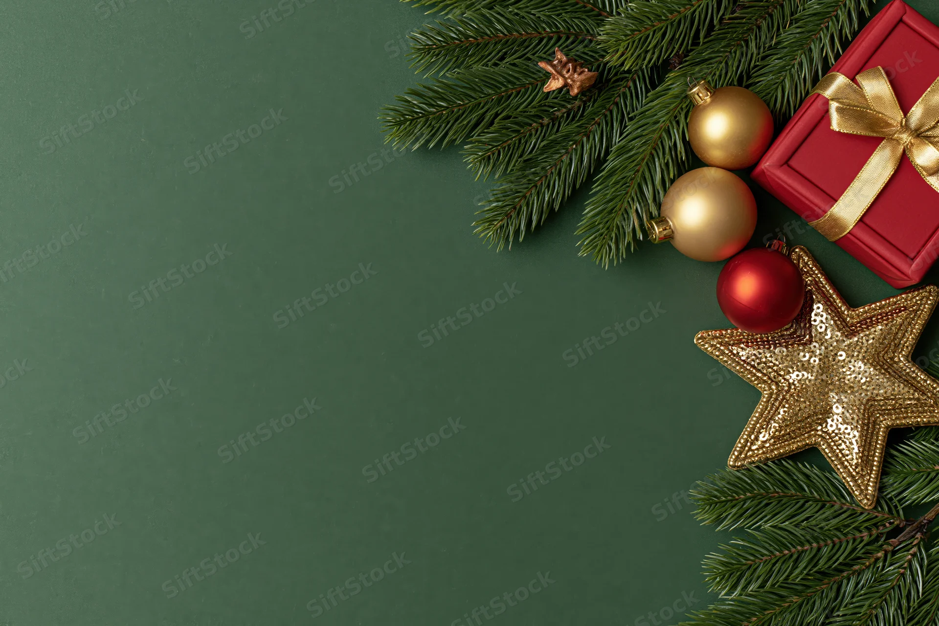 Christmas decorations and gift box arranged on green surface with copyspace