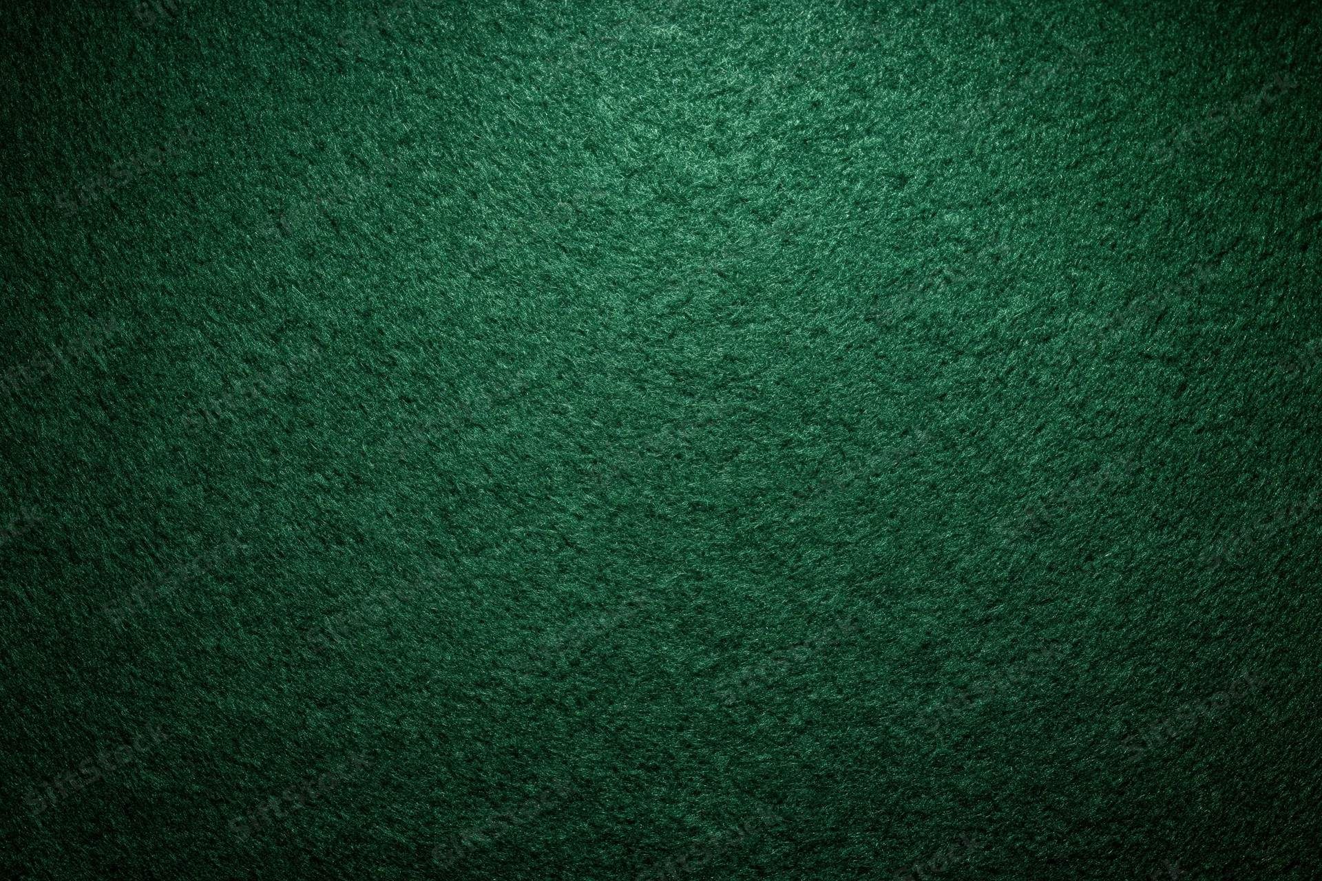 Close-up of green felt poker table surface with textured grain and dim lighting