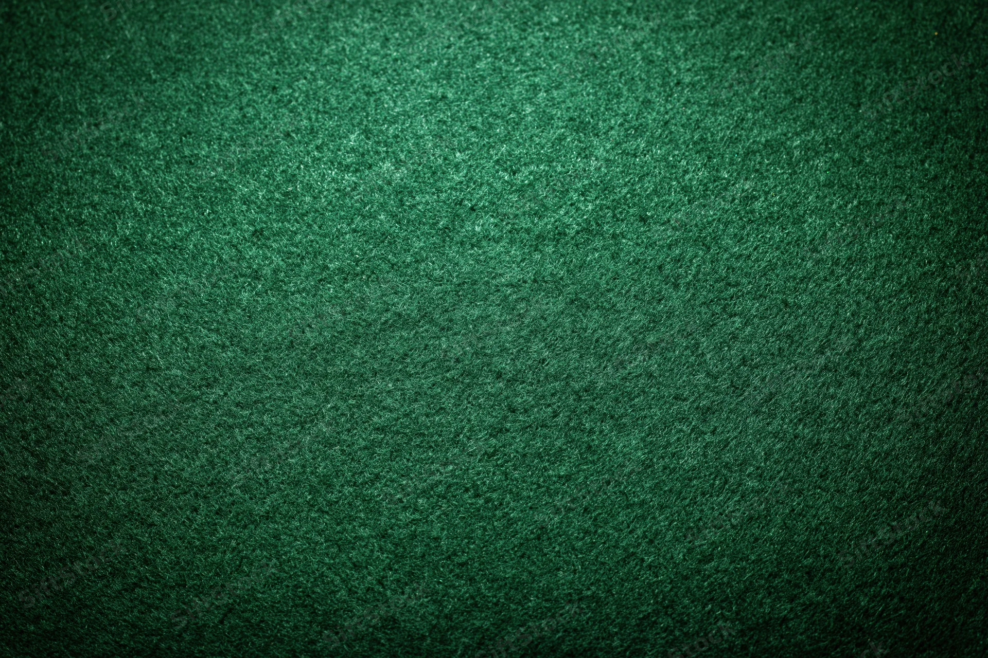 Close-up of green felt poker table surface with textured fabric and subtle lighting gradient