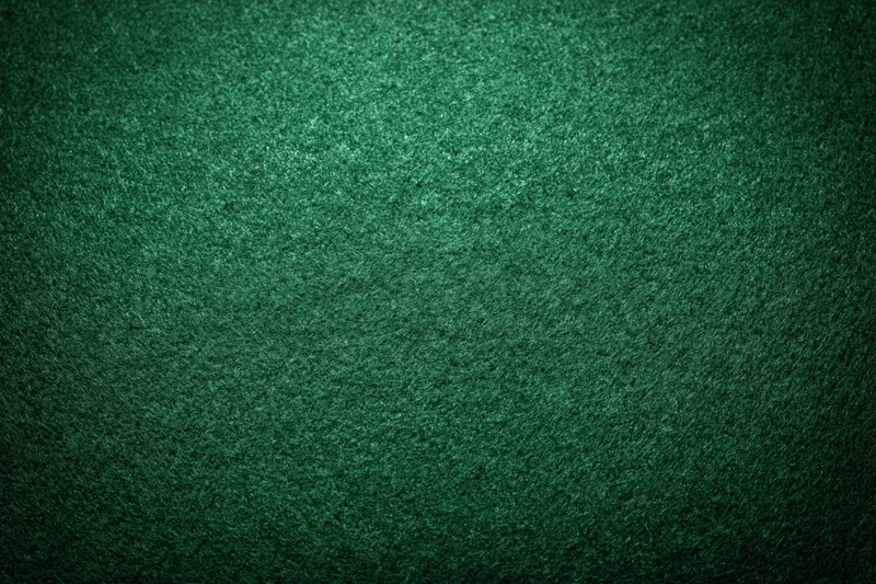 Close-up of green felt poker table surface with textured fabric and subtle lighting gradient