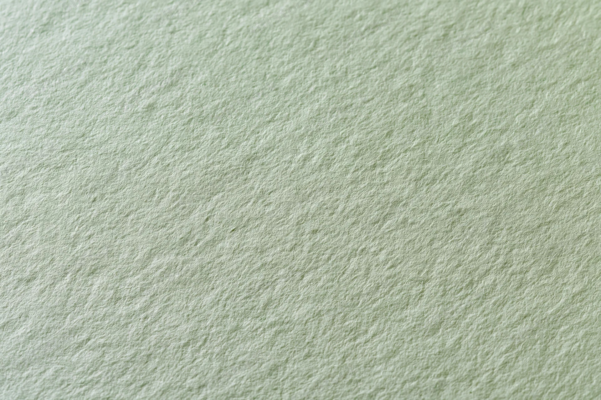 Close-up of a single sheet of pale sage green matte paper lying flat, showing its textured surface and even tone