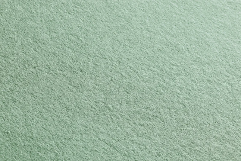 Close-up of a single sheet of pale sage green matte paper laid flat