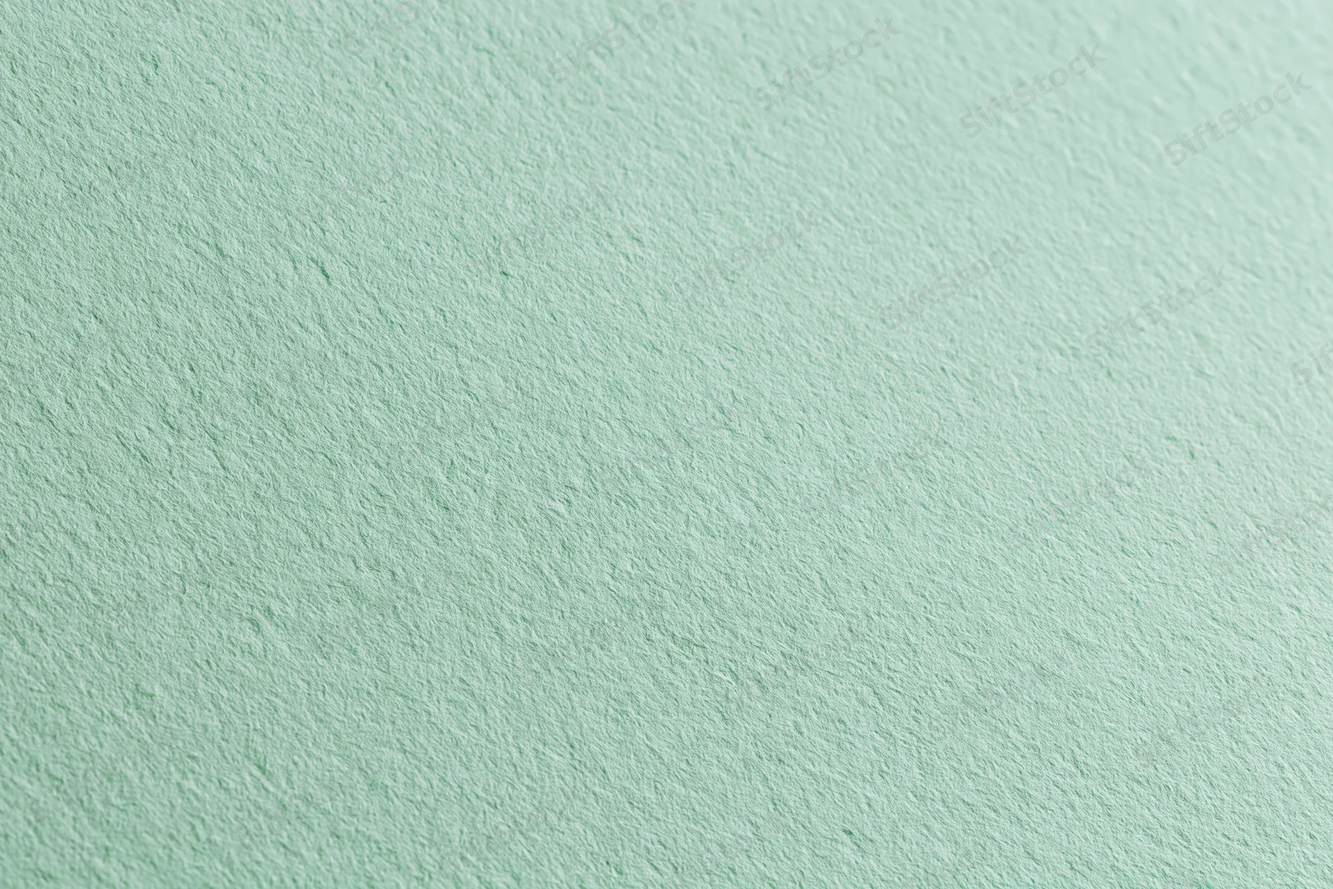 Close-up of a pale sage green matte paper sheet with textured surface