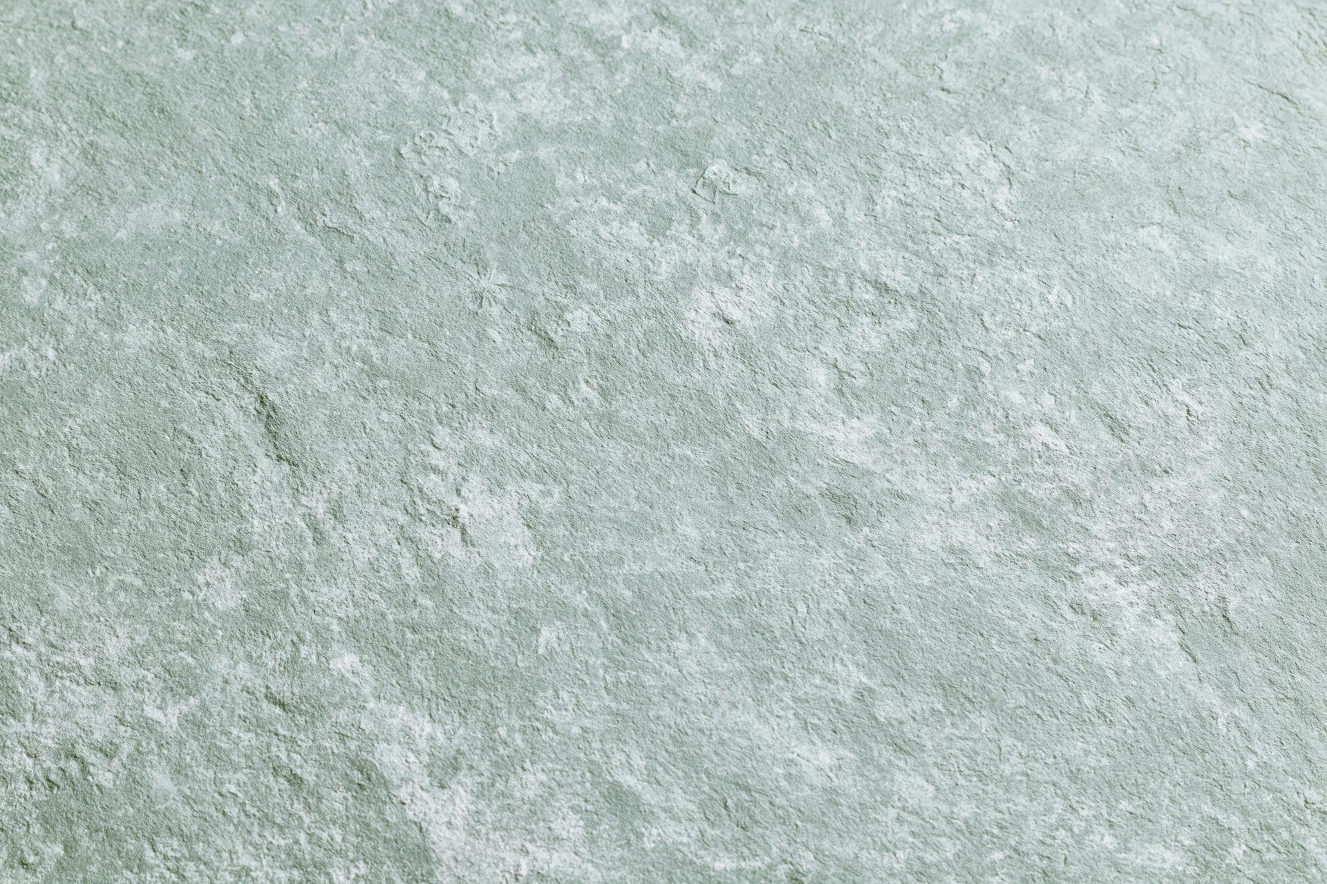 Close-up of a weathered concrete wall surface with textured gray and mint green finish