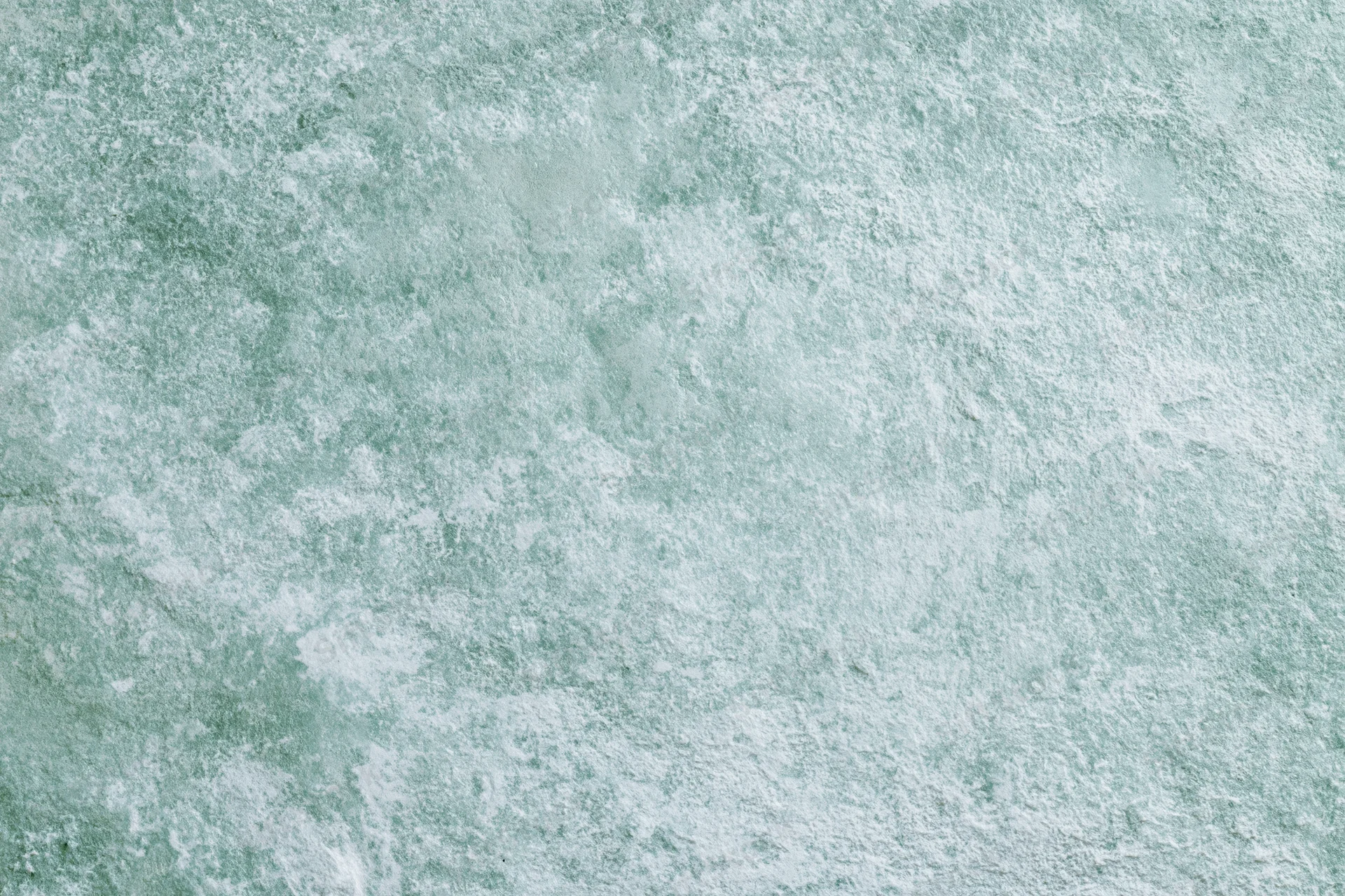 Close-up of a weathered concrete wall surface with greenish-gray texture and speckled pattern