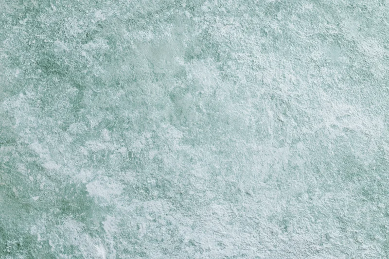Close-up of a weathered concrete wall surface with greenish-gray texture and speckled pattern