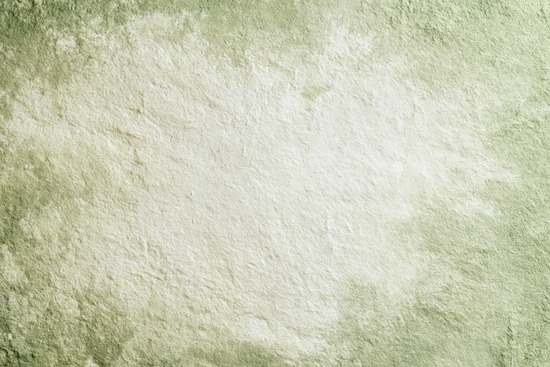 Close-up of aged plaster wall surface with distressed texture and muted green beige tones