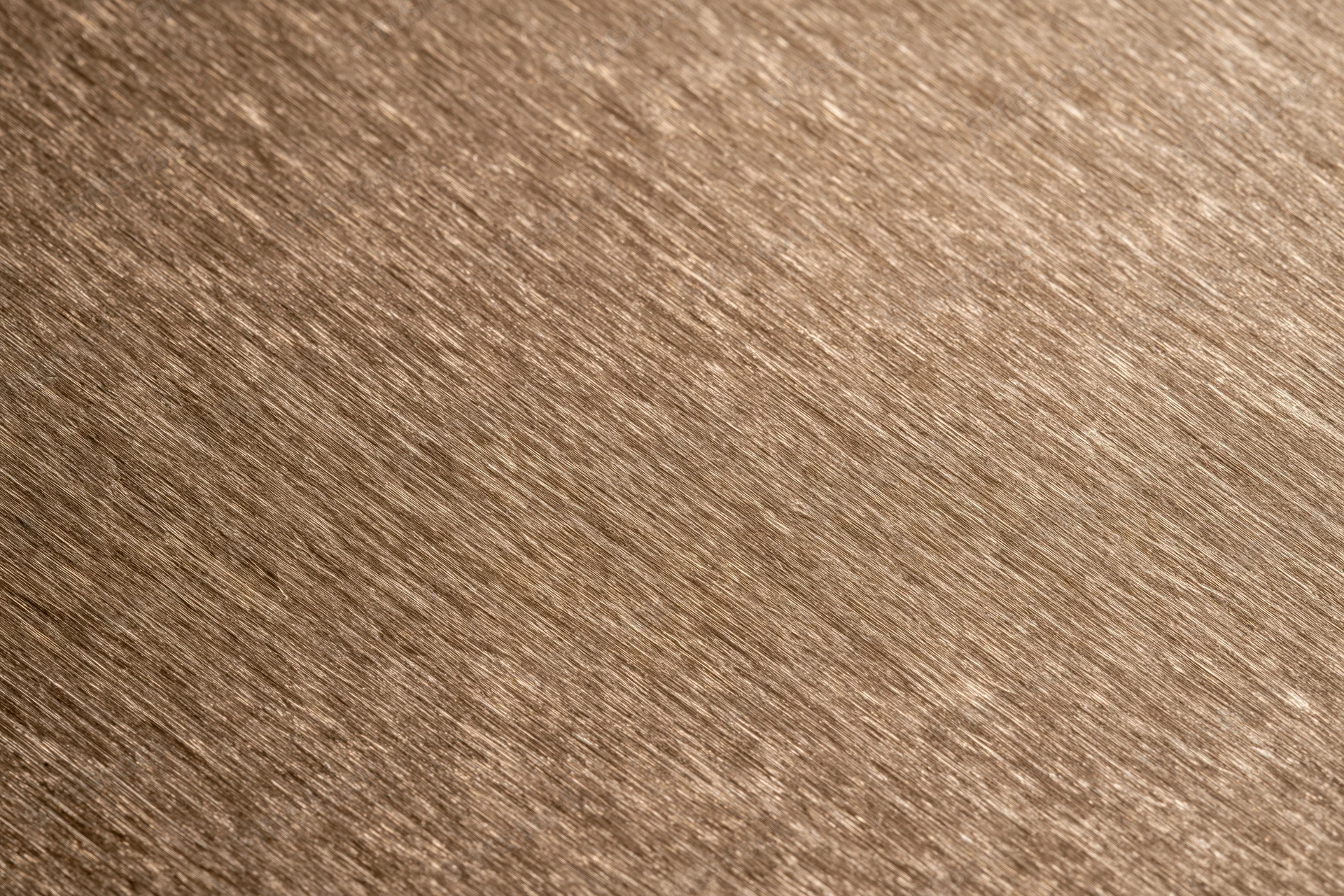 Close-up of brushed bronze metal surface with diagonal grain pattern filling the frame