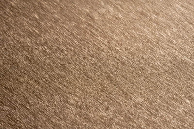 Close-up of brushed bronze metal surface with diagonal grain pattern filling the frame