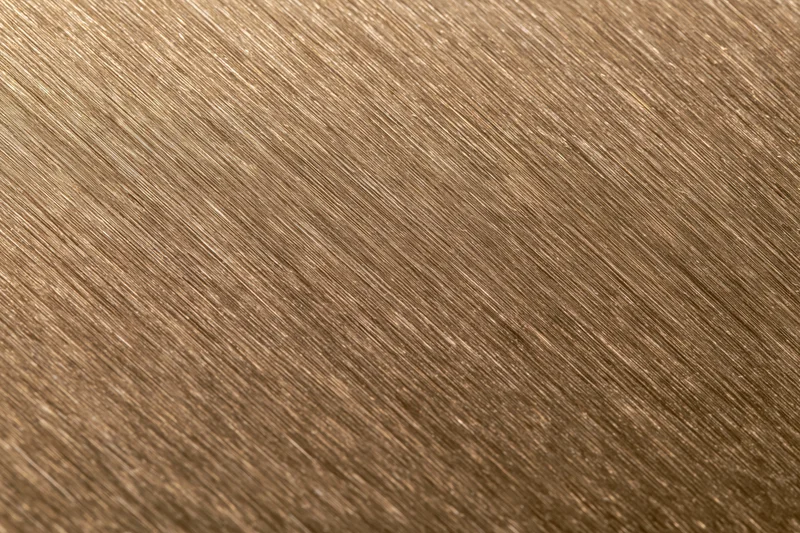 Close-up of brushed bronze metal surface with diagonal texture pattern