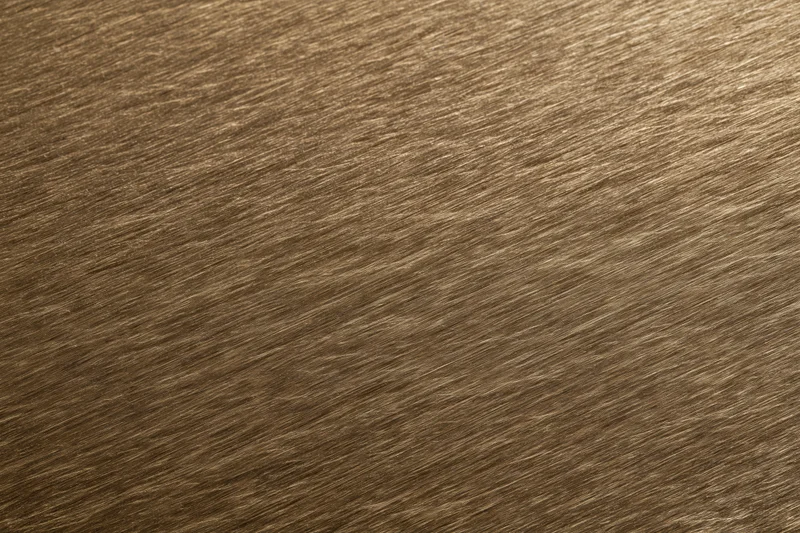 Close-up of brushed bronze metal surface with linear texture filling the frame
