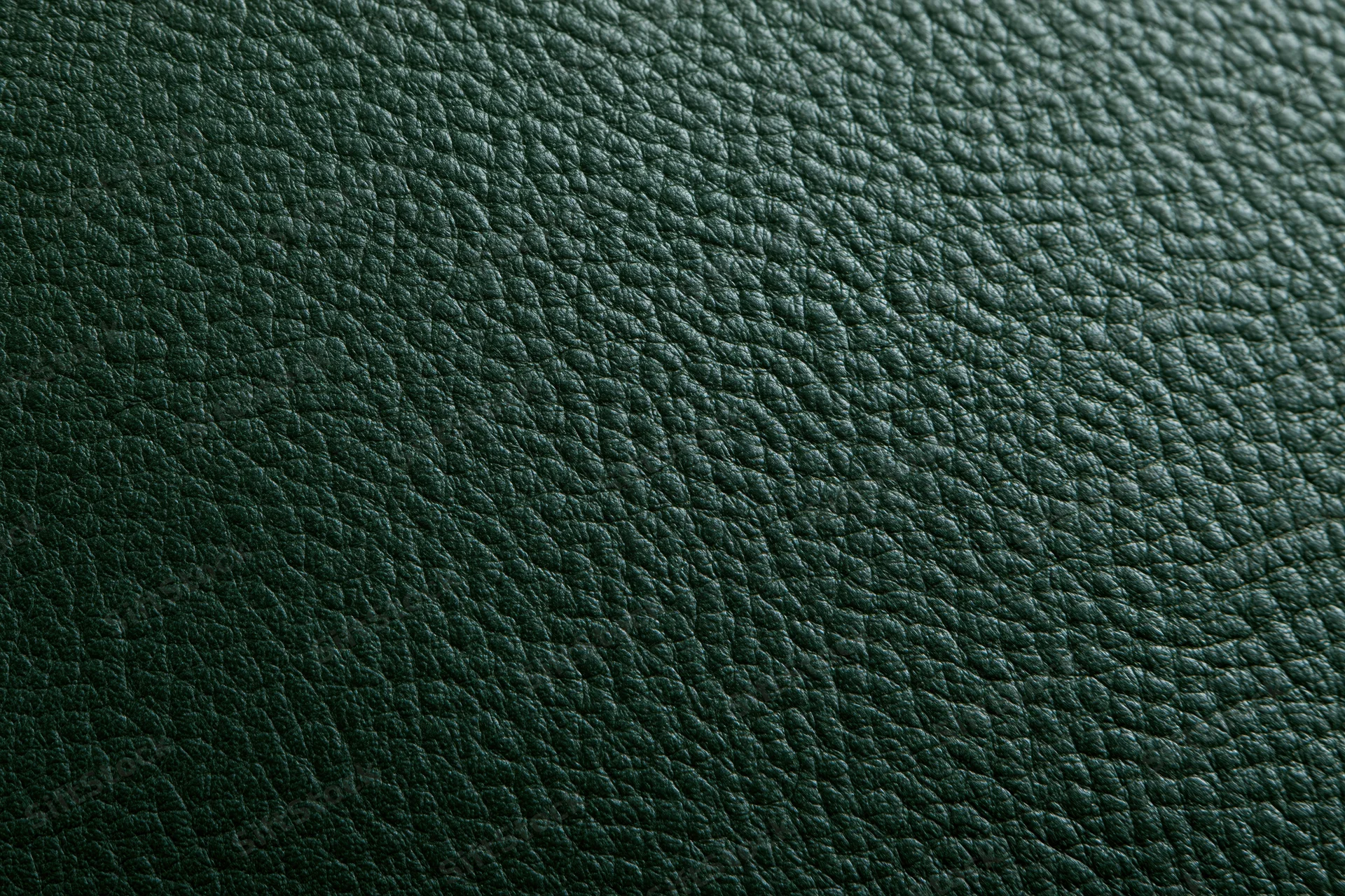 Close-up of dark forest green leather surface with pebbled texture filling the frame