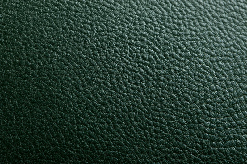 Close-up of dark forest green leather surface with pebbled texture filling the frame