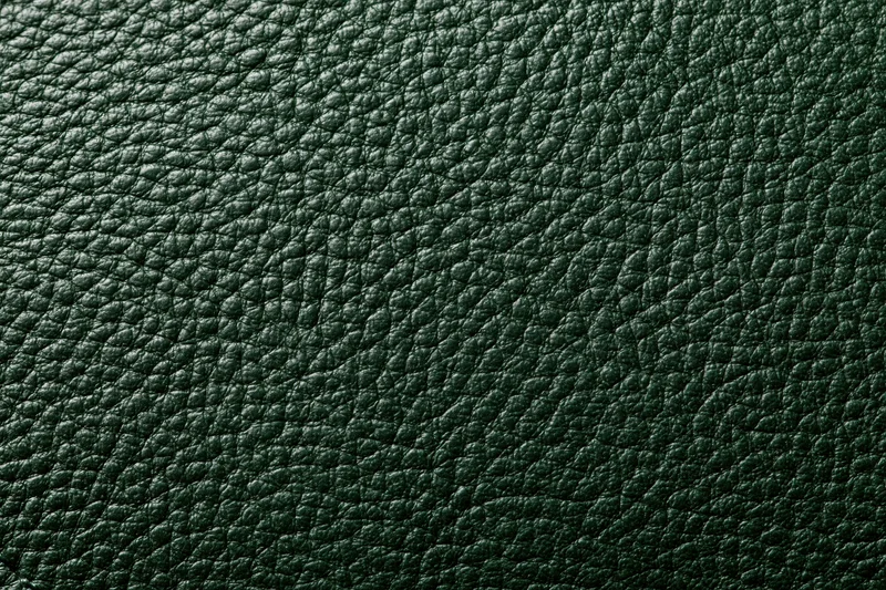 Close-up of dark forest green leather surface with pebbled texture filling the frame
