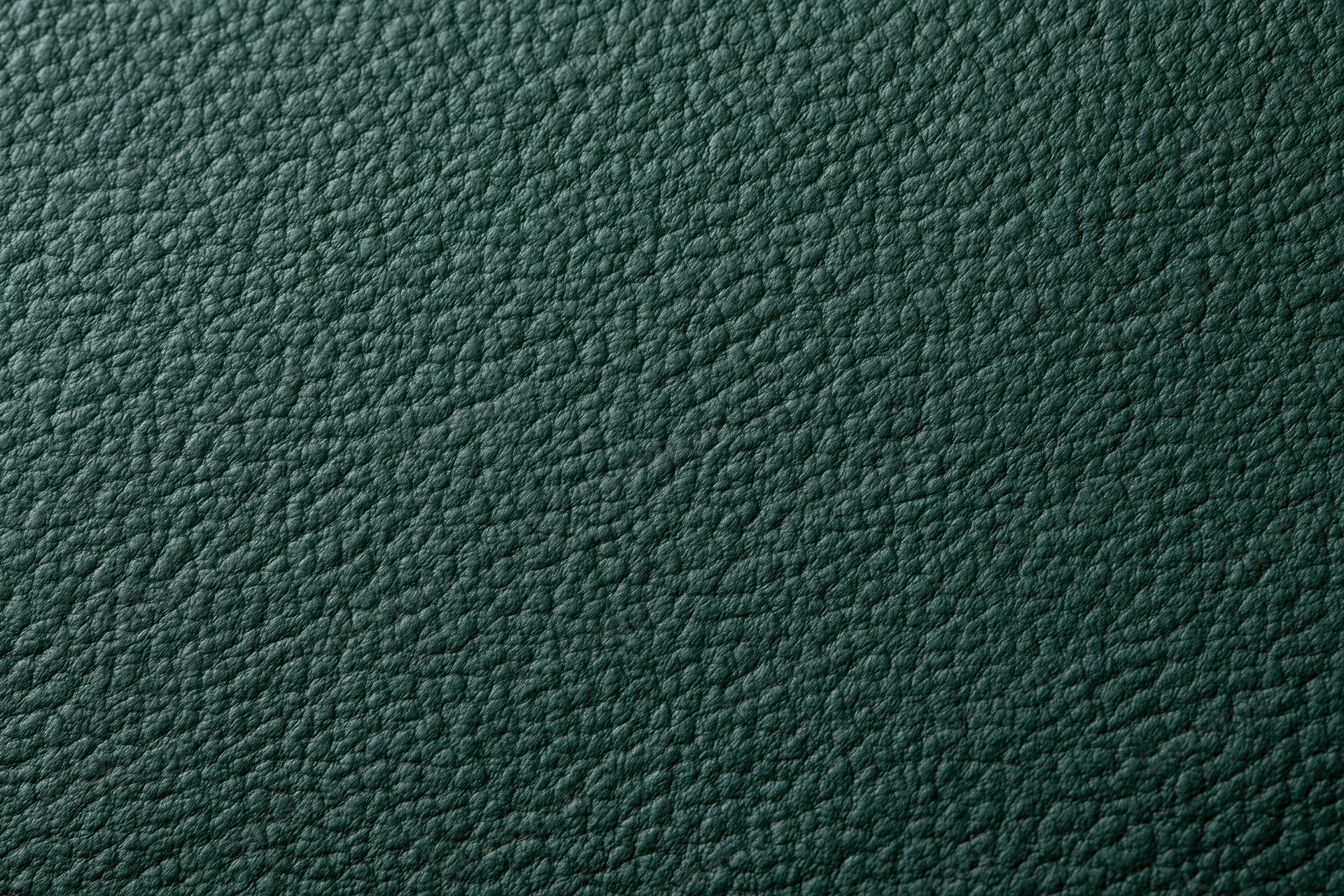 Close-up of dark forest green leather surface with pebbled texture filling the frame