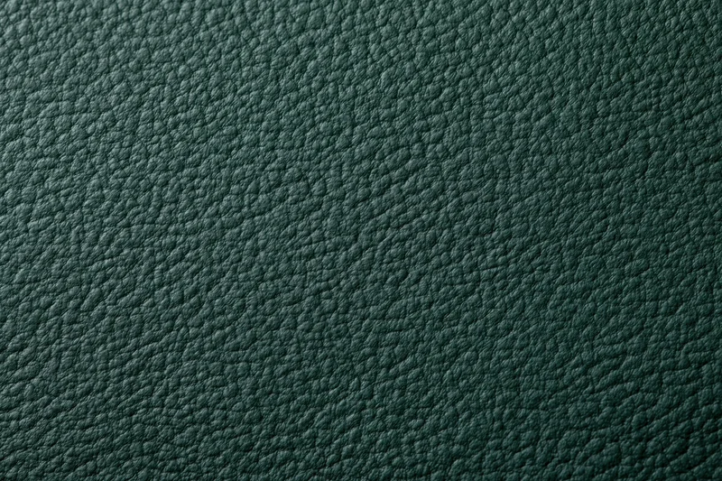 Close-up of dark forest green leather surface with pebbled texture filling the frame