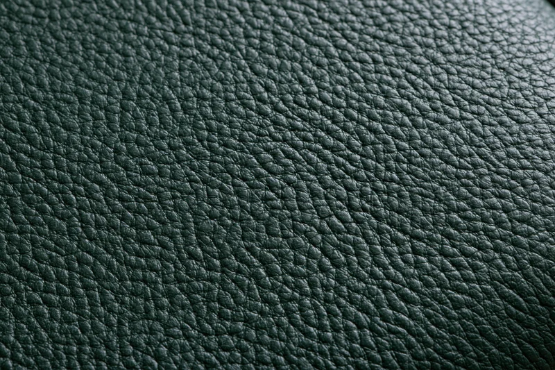 Close-up of dark forest green leather surface with pebbled texture filling the frame