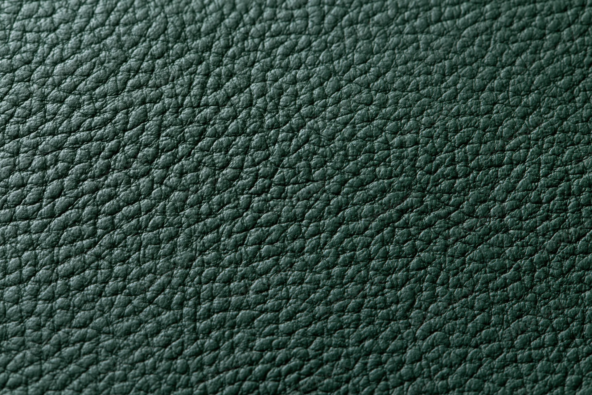 Close-up of dark forest green leather surface showing pebbled texture and grain pattern