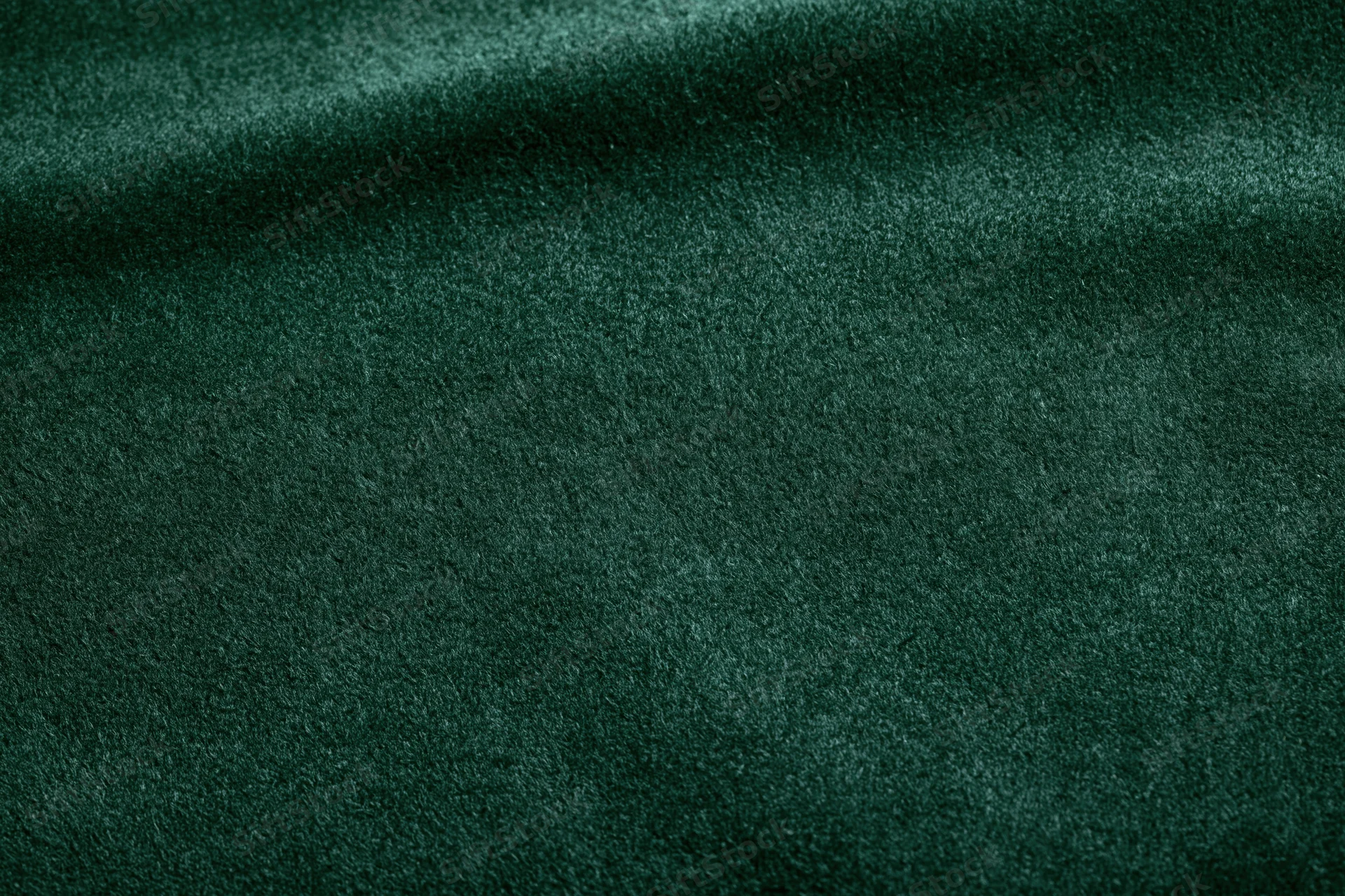 Close-up of dark forest green velvet fabric with soft texture and folds