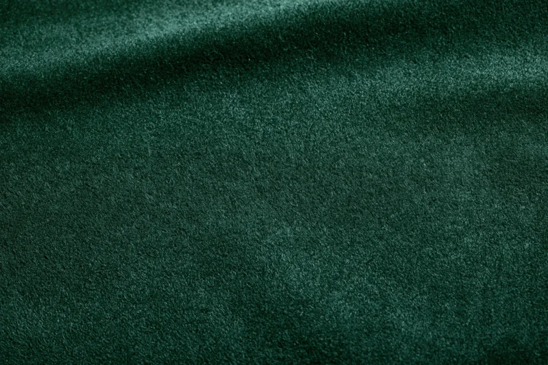 Close-up of dark forest green velvet fabric with soft texture and folds