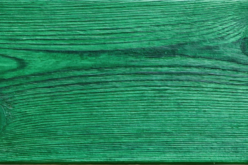 Close-up of green-painted wooden surface showing natural grain and texture