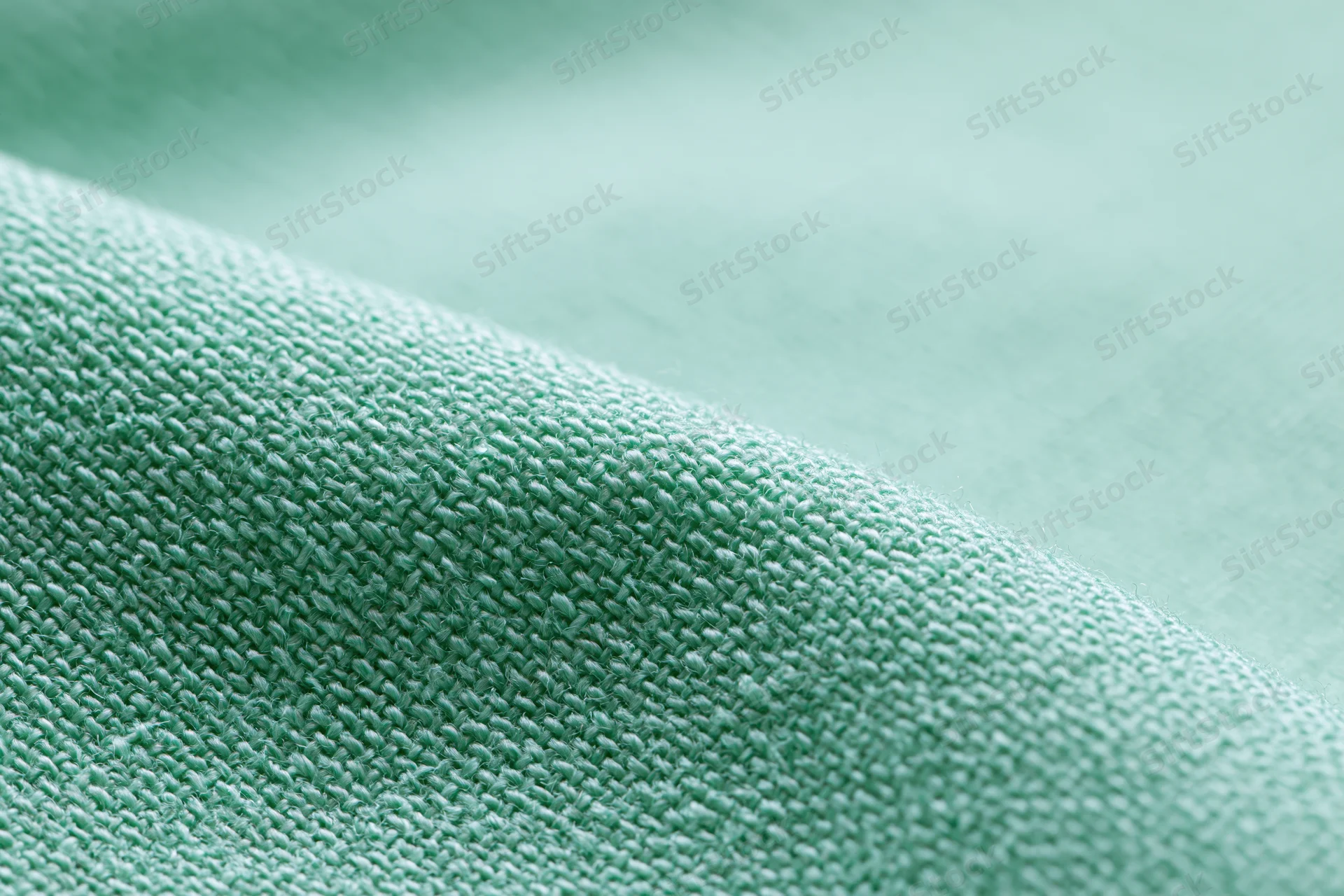 Close-up of light mint green woven fabric with visible texture and weave pattern