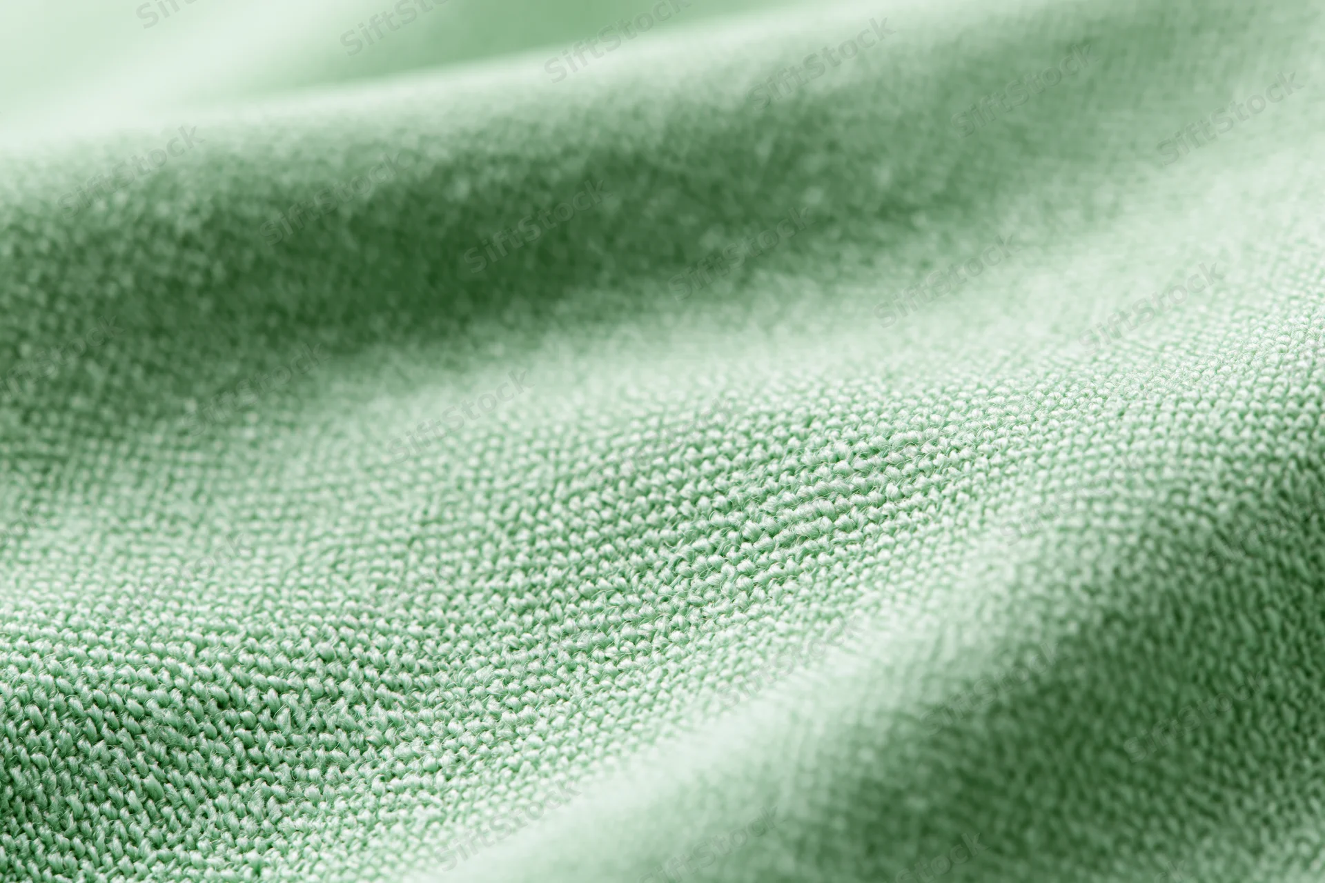 Close-up of light mint green woven fabric with visible texture and soft folds