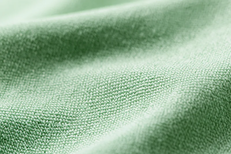 Close-up of light mint green woven fabric with visible texture and soft folds