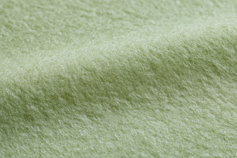 Close-up of light sage green felt fabric with soft fibrous texture filling the frame