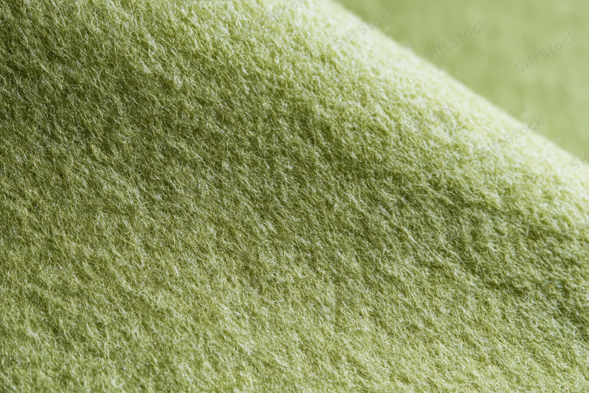 Close-up of light sage green felt fabric with soft fibrous texture filling the frame