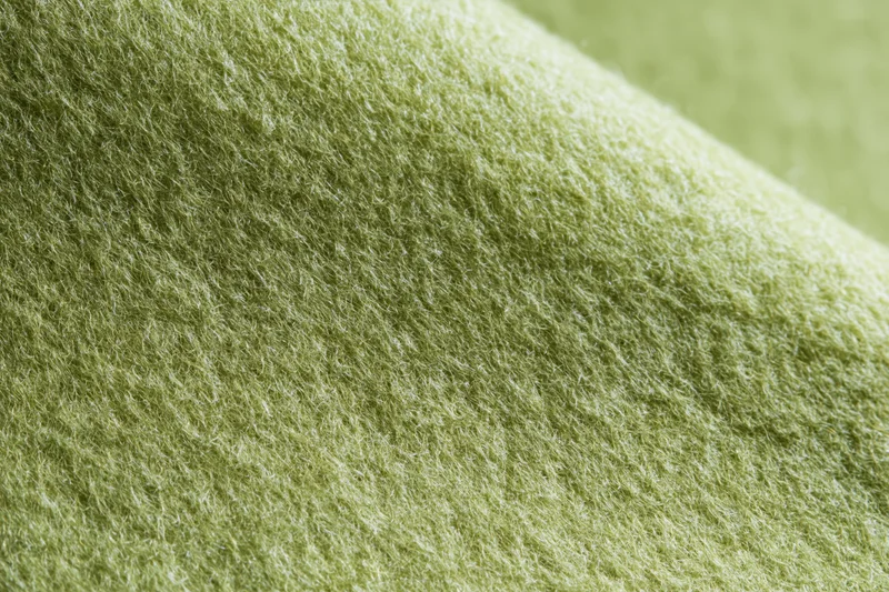 Close-up of light sage green felt fabric with soft fibrous texture filling the frame