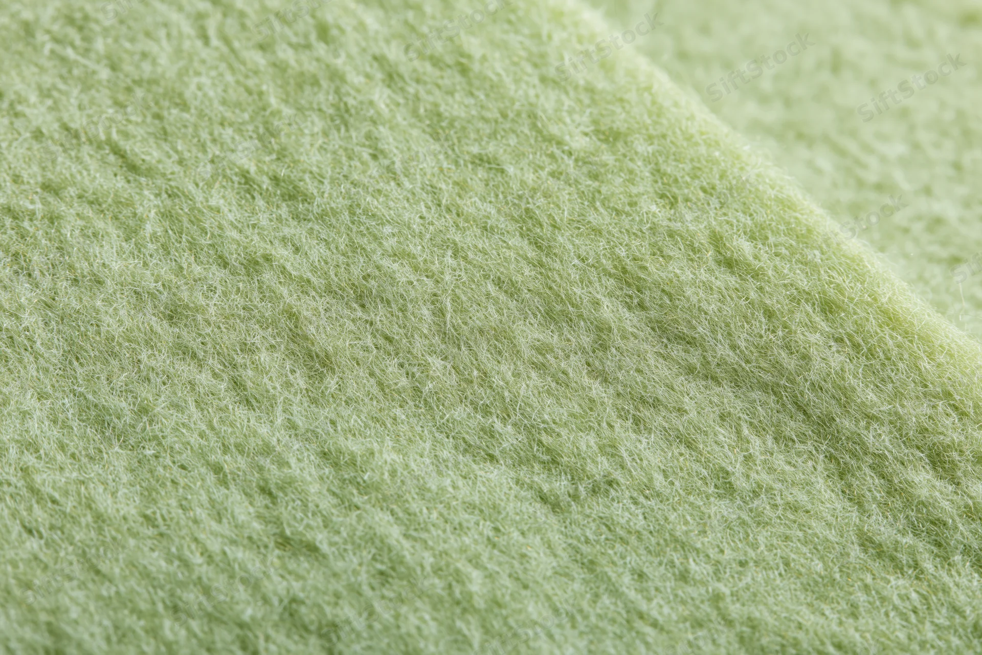 Close-up of light sage green felt fabric with fibrous texture filling the frame
