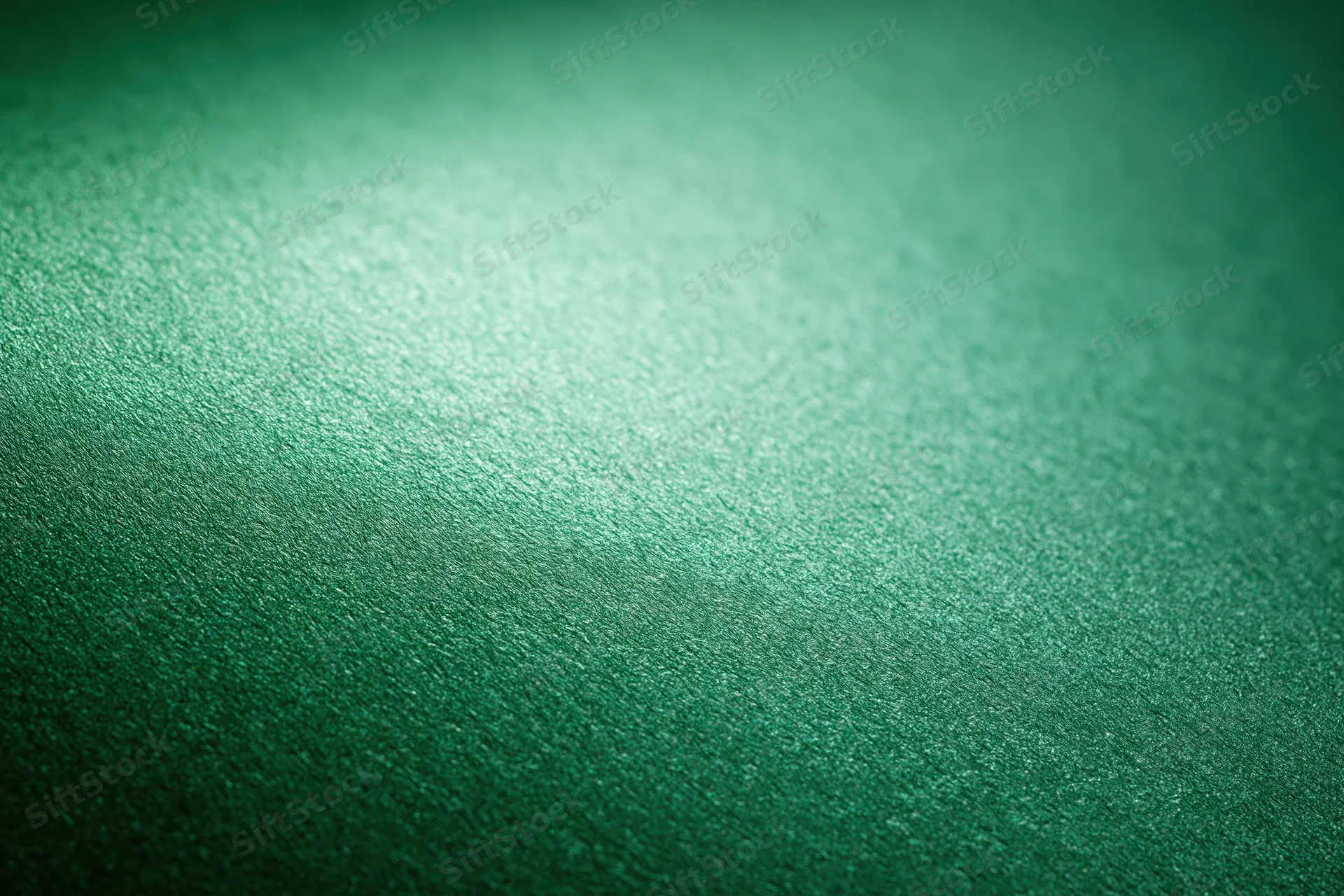 Close-up of metallic green textured paper surface with subtle gradient and reflective sheen