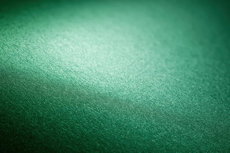 Close-up of metallic green textured paper surface with subtle gradient and reflective sheen