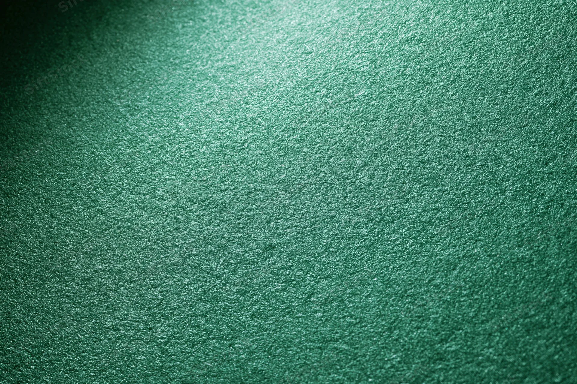 Close-up of metallic green textured paper surface with light gradient
