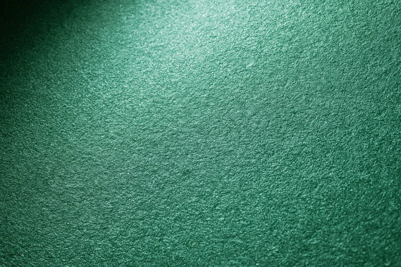 Close-up of metallic green textured paper surface with light gradient