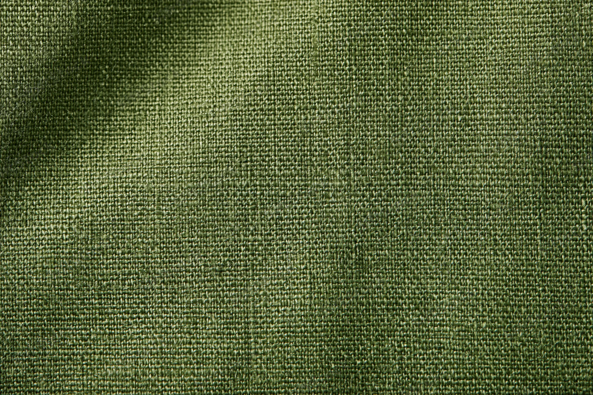 Close-up of olive green linen fabric with visible weave pattern filling the frame