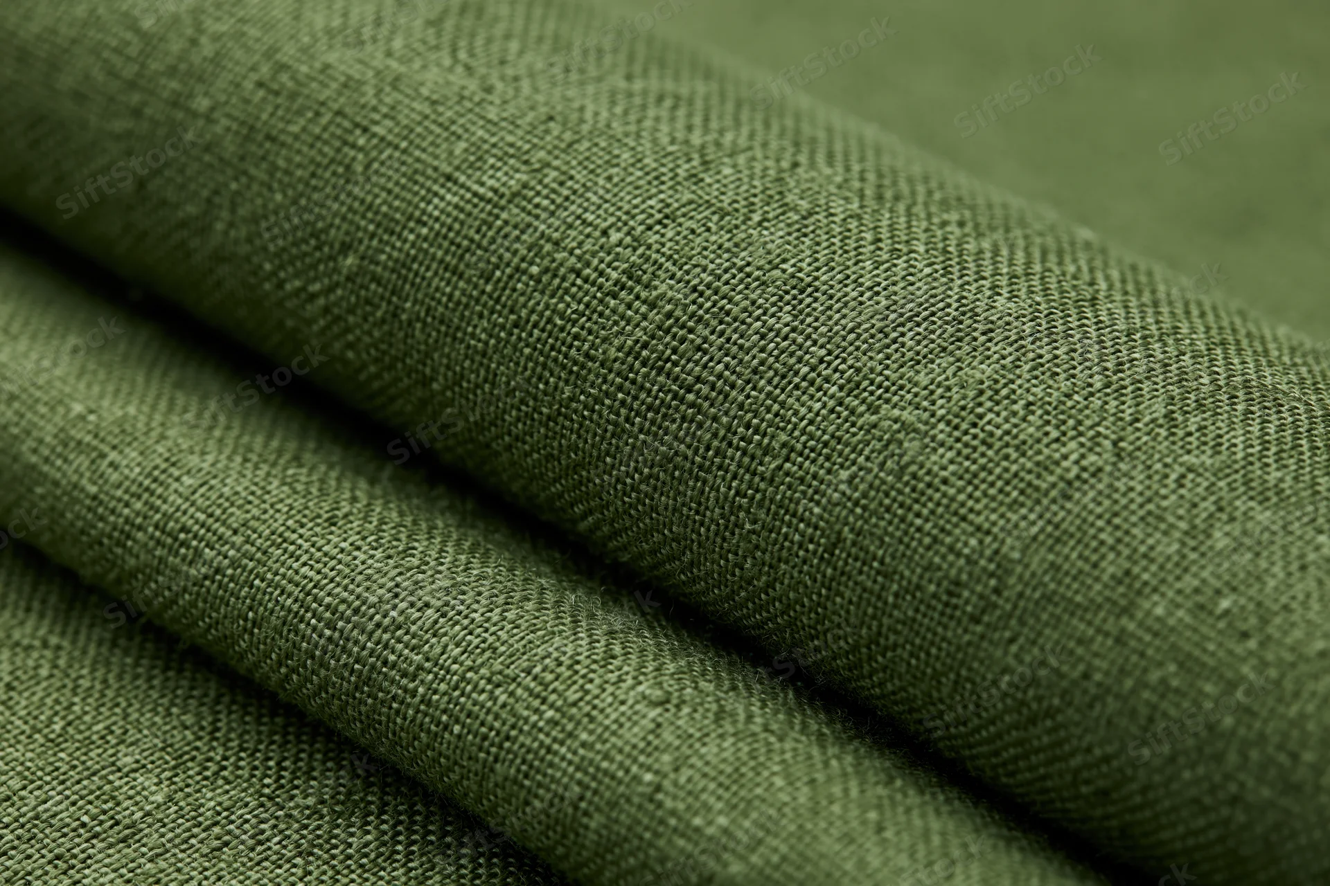 Close-up of folded olive green linen fabric showing woven texture in flat lay arrangement