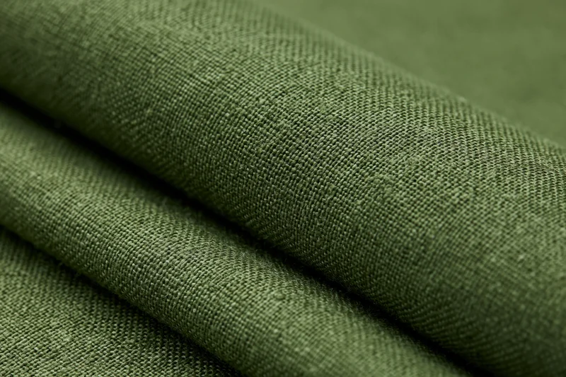 Close-up of folded olive green linen fabric showing woven texture in flat lay arrangement