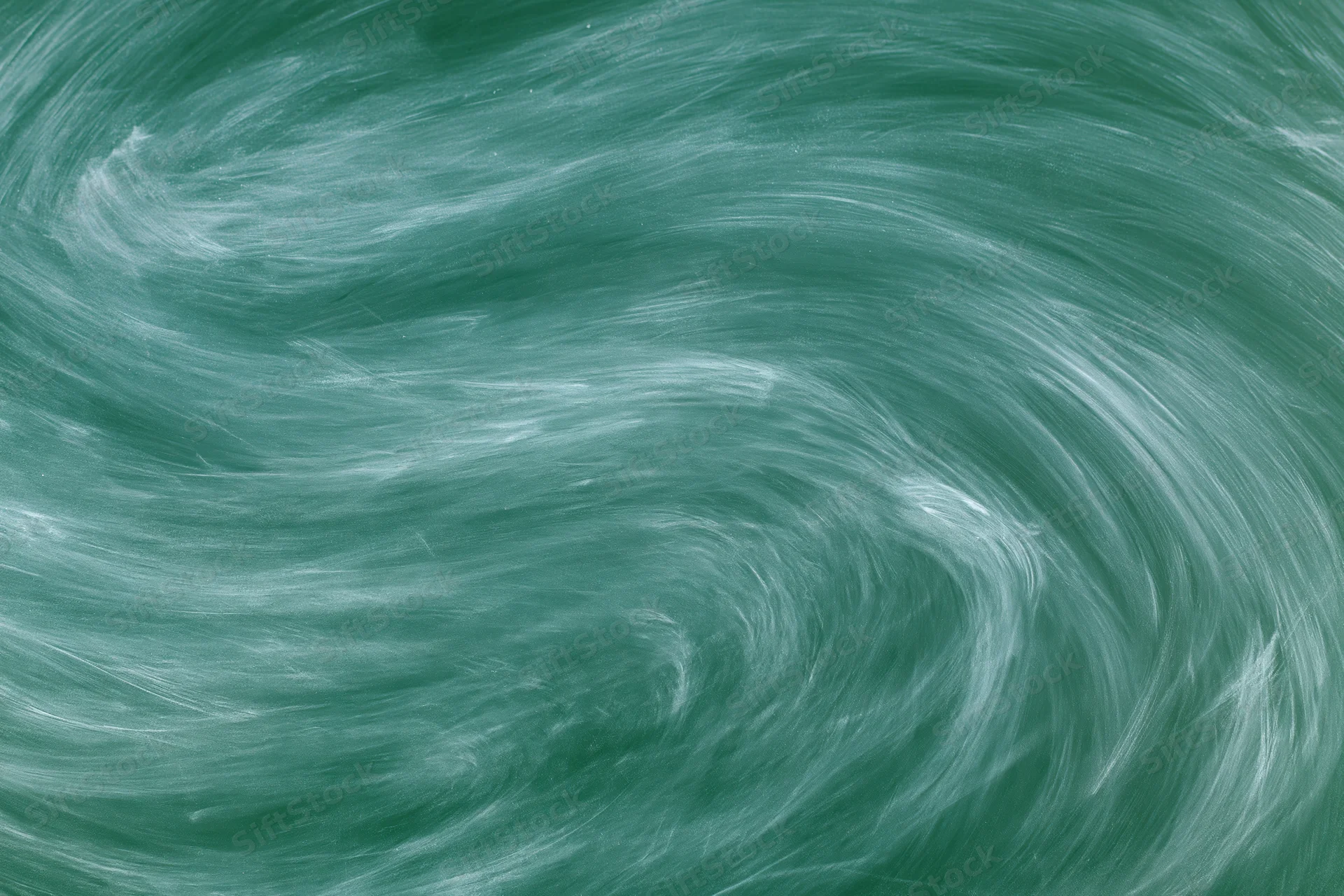 Close-up of a green chalkboard surface with swirling white chalk residue after erasing
