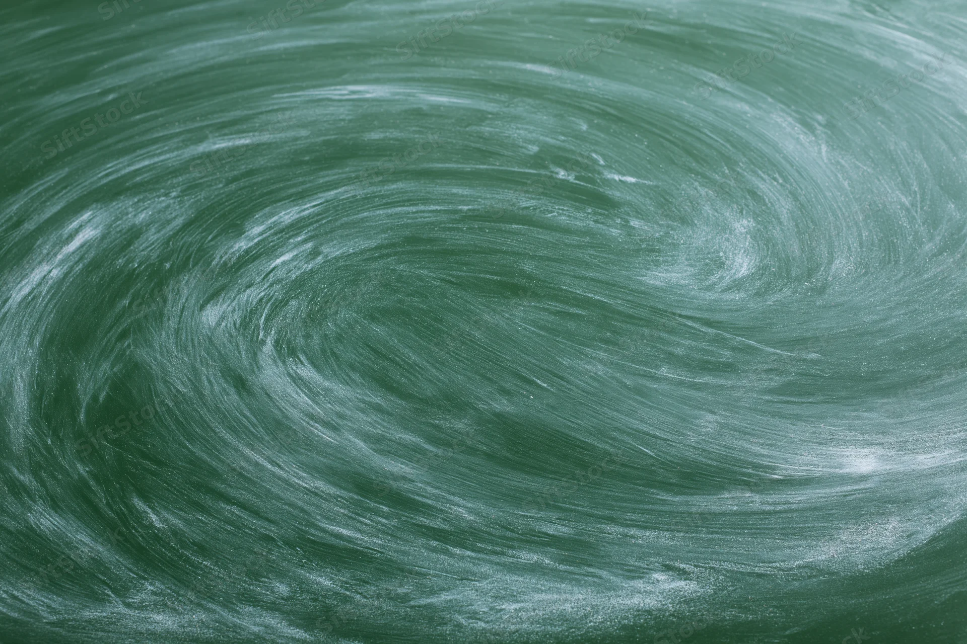 Close-up of a green chalkboard surface with swirling chalk residue from erasing