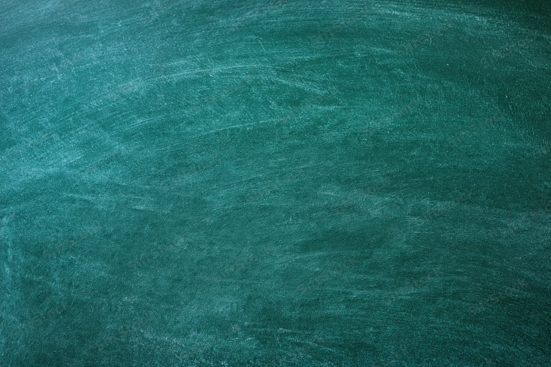Close-up of a worn green chalkboard surface with smudged marks and dust residue
