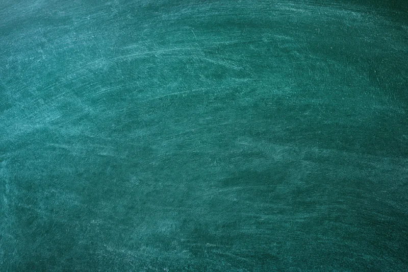 Close-up of a worn green chalkboard surface with smudged marks and dust residue