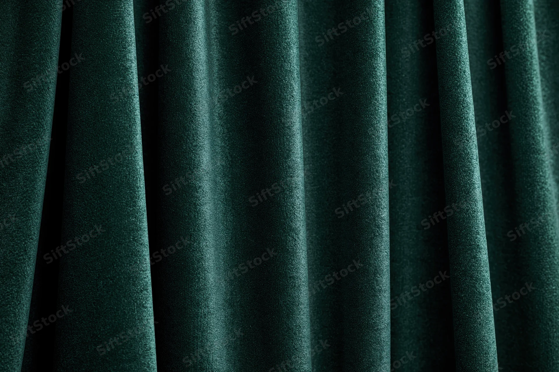 Close-up of heavy dark emerald green velvet curtain with deep folds and rich texture