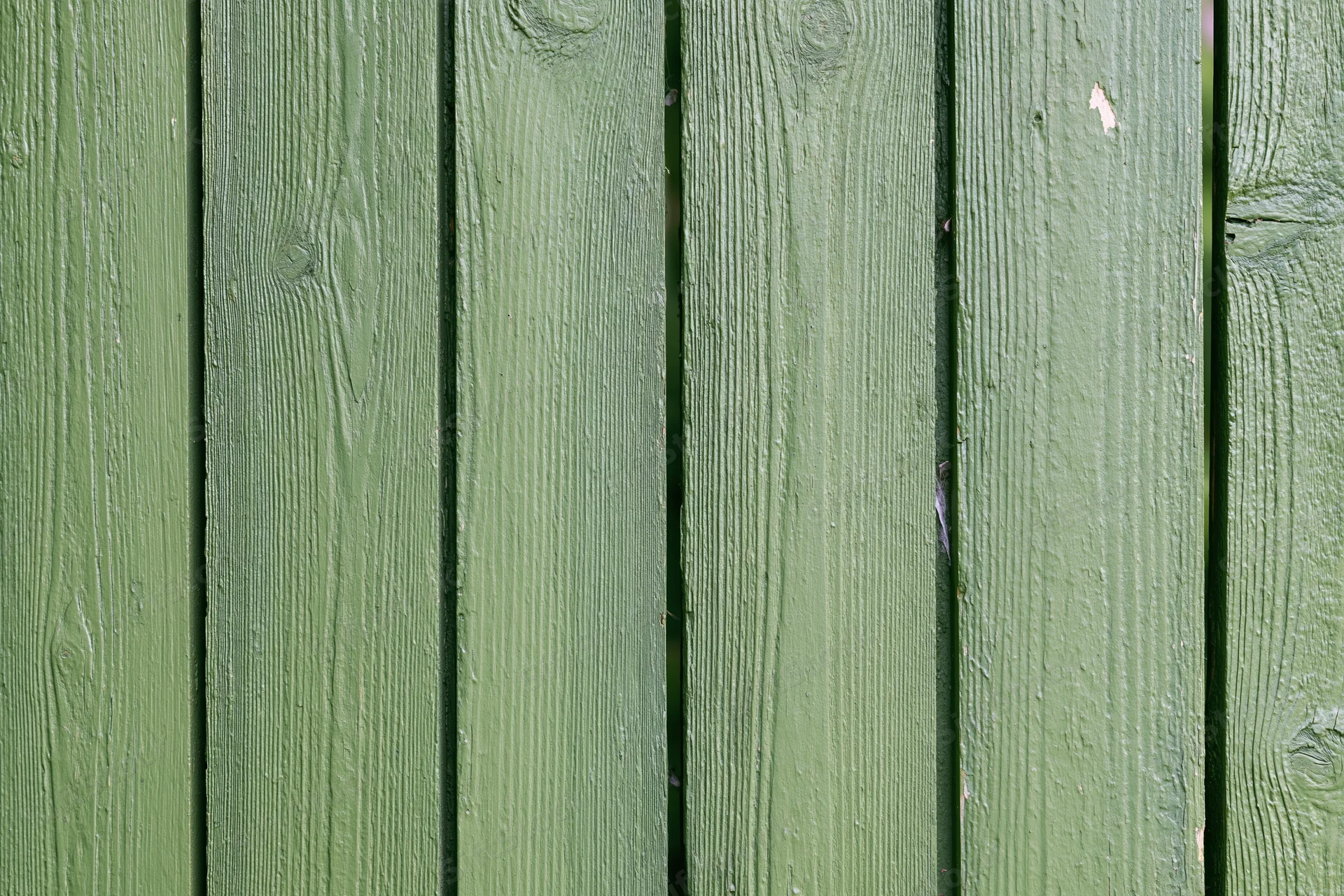 Vertical green painted wooden planks showing weathered texture and grain as outdoor fence surface