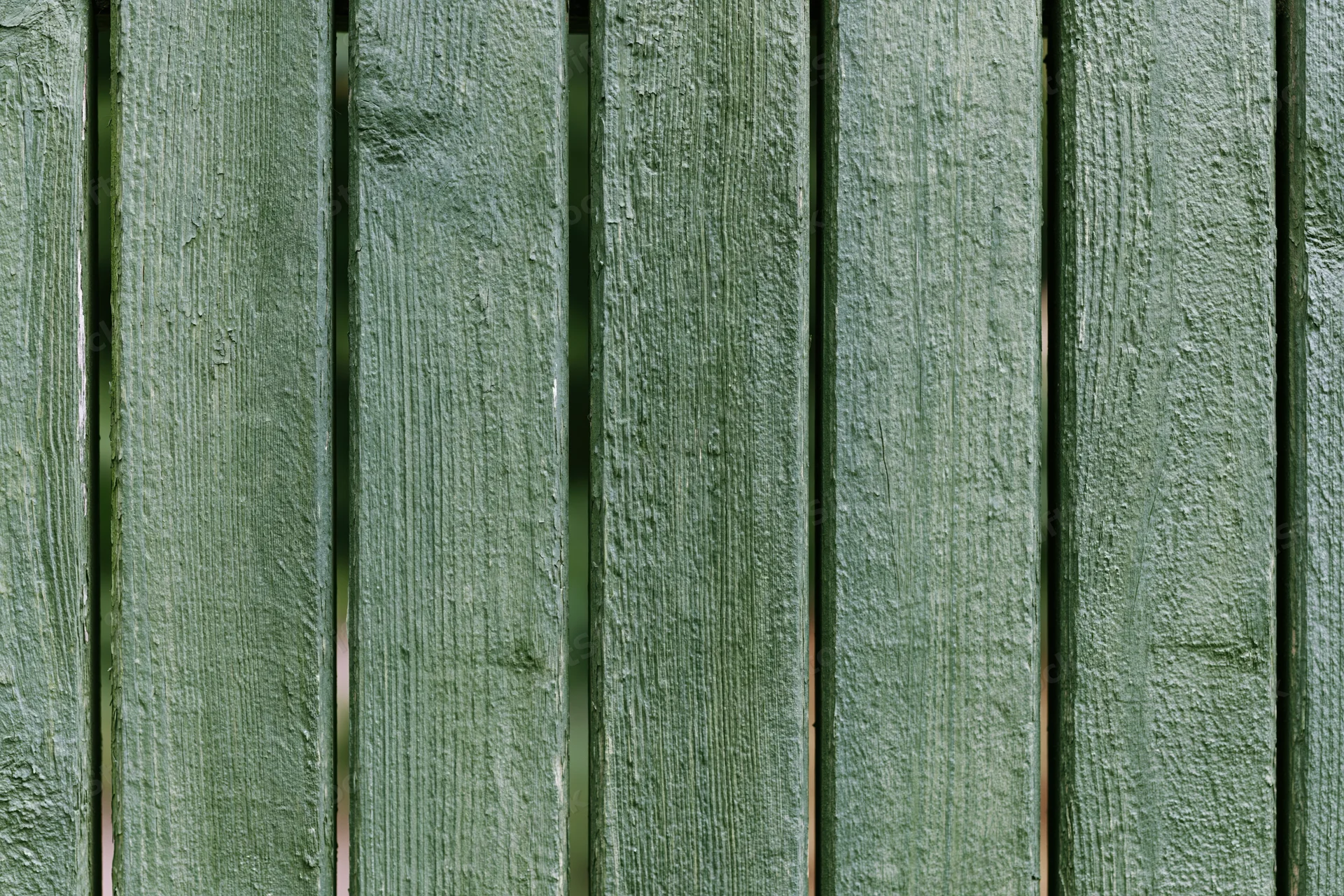 Vertical green painted wooden planks forming a weathered outdoor fence surface