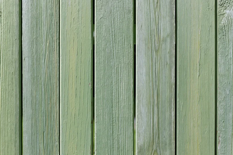 Vertical weathered green wooden planks forming a garden fence surface